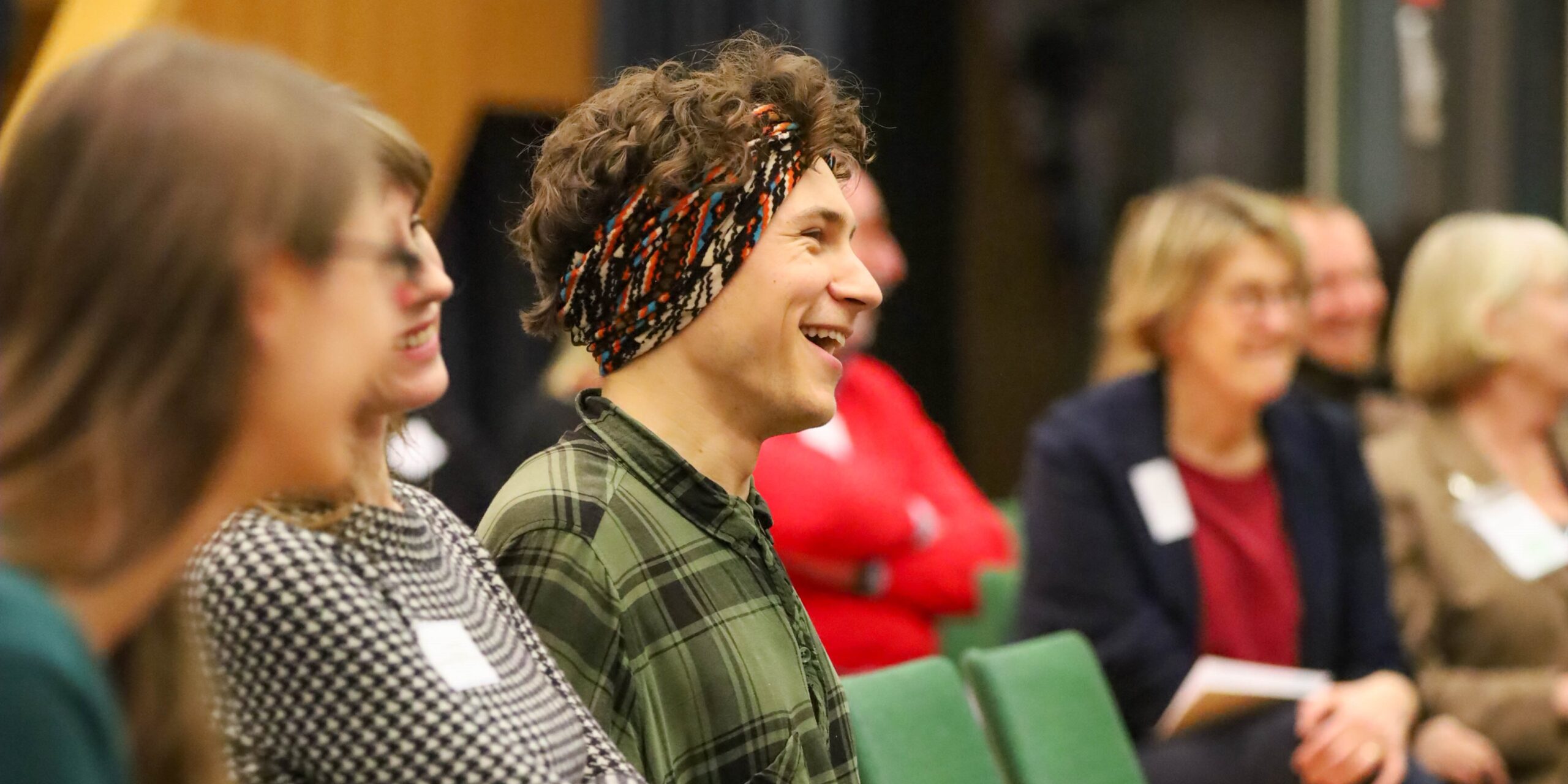 Ein lachender junger Mann auf einer Konferenz.