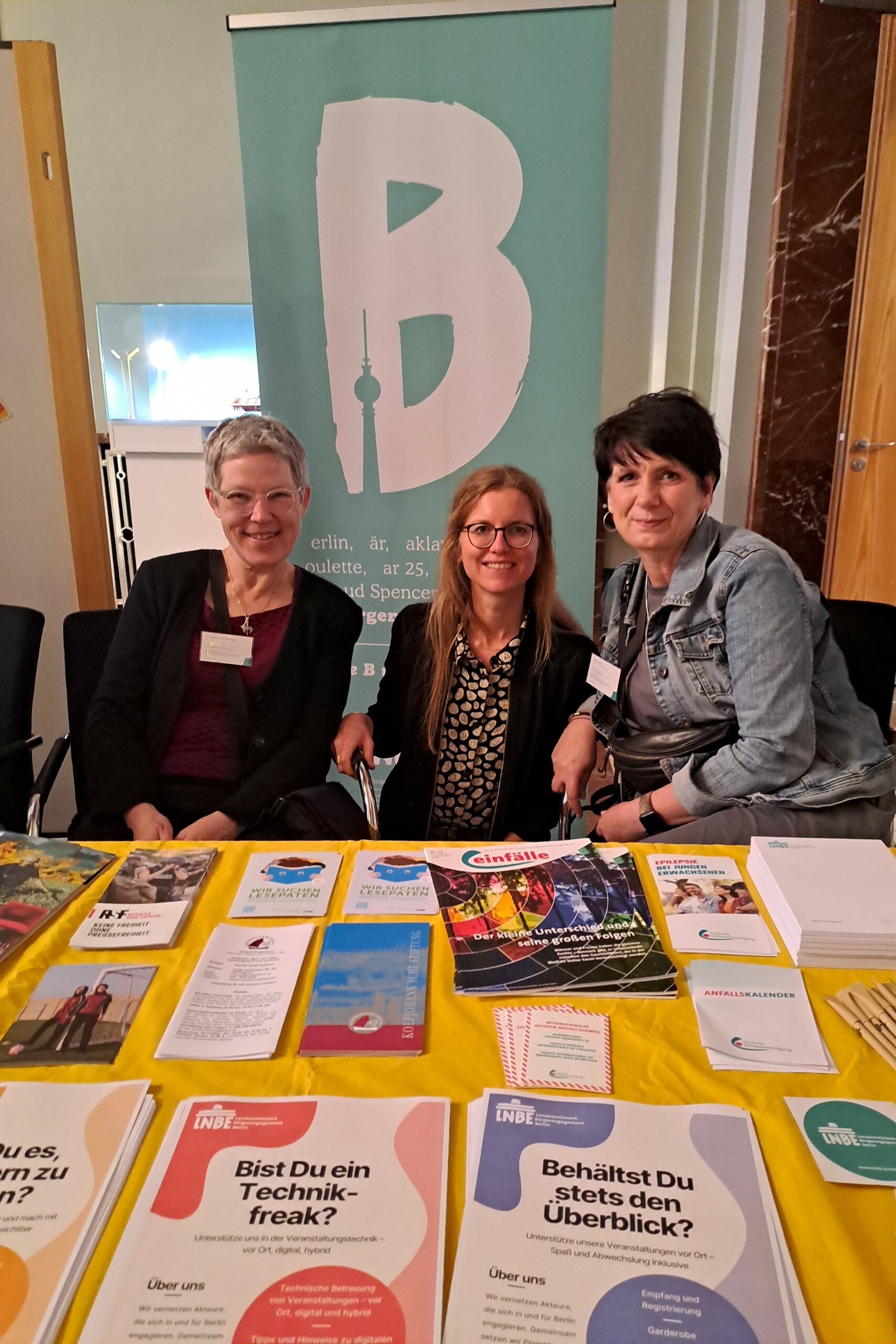 Gruppenbild von drei Frauen, die einen Stand auf der Berliner Freiwilligenbörse betreuen.